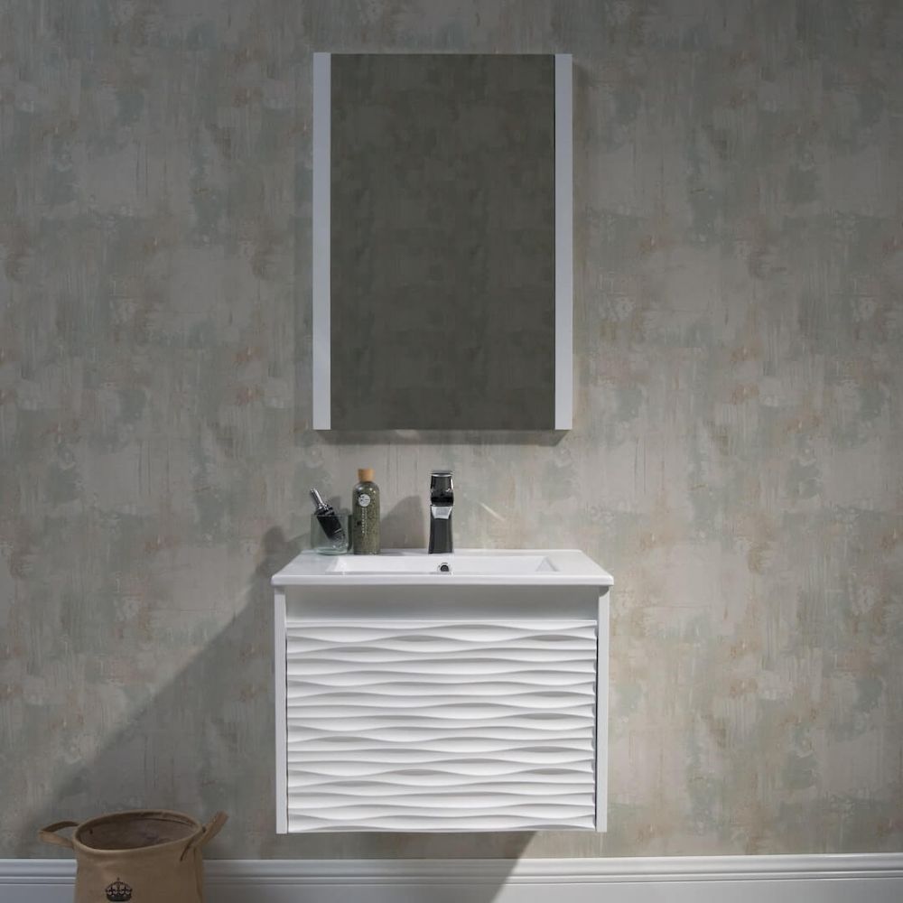 A modern bathroom setup with a textured white vanity and sink, a rectangular mirror above, a dark faucet, and toiletries. The wall has a subtle patterned wallpaper, and a woven basket is on the floor to the left.