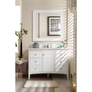 A bright bathroom showcases the Palisades 48-inch Bathroom Vanity in Bright White with six drawers and a large mirror above. A potted plant and towels rest on the countertop. Black-and-white modern artwork adorns the wall, while a soft rug graces the light-tiled floor.
