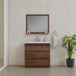 A modern bathroom showcases the Paterno 48 Freestanding Bathroom Vanity with Sink in Rosewood paired with a rectangular mirror. A small white shelf for toiletries and a towel hang on the right, complemented by a potted plant on the floor and beige tiled walls and floors.