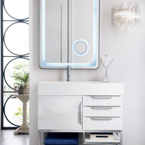 The Columbia 36 Single Bathroom Vanity in glossy white hosts a sleek sink and cabinet, paired with an illuminated mirror above. Its drawers and open shelves hold folded towels, while a decorative plant and glass elements enhance the elegant, contemporary bathroom setting.