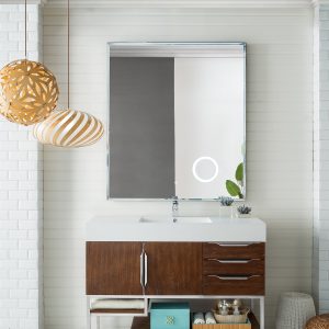 A modern bathroom features the Columbia 48 Single Bathroom Vanity in Coffee Oak with Brushed Nickel accents. A large square mirror reflects decorative pendant lights, a tray with soaps, a folded towel, and a small green plant.