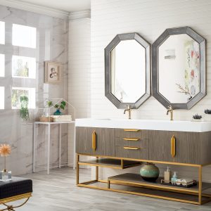 A modern bathroom showcases the Columbia 72 Double Bathroom Vanity in Ash Gray and Radiant Gold, topped with a white countertop and paired with two octagonal mirrors. Decorative items enhance the vanity and shelves, while large grid-patterned windows illuminate the space.