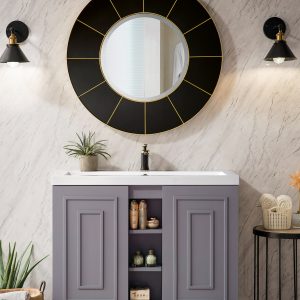 The Alicante 39.5 Bathroom Vanity in Grey Smoke and Matte Black includes a large circular mirror with two overhead wall sconces, cabinets, open shelving for decor, and is styled with a small plant and towel on the left plus a stand with towels and decor on the right.