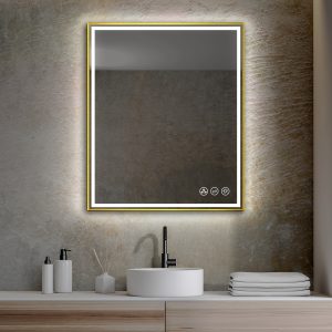 In a modern bathroom, a Stellar 30 Inch LED Bathroom Mirror with a gold frame is mounted above a sleek white vessel sink. The countertop displays folded towels, soap dispensers, and a reed diffuser, while the wall features a textured stone finish.