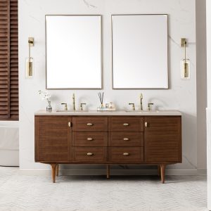 Experience luxury with the Amberly 72 Double Vanity in Mid-Century Walnut featuring an Eternal Marfil top, complemented by square mirrors. Brass faucets and fixtures add elegance, while a light herringbone floor pattern and softly textured walls create a serene backdrop.
