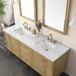The Laurent 72 Double Bathroom Vanity Cabinet in Natural Oak features a light marble countertop with dual sinks, gold faucets, wooden cabinets, and two large wood-framed mirrors. It includes a plant and neatly arranged toiletries on the dark tile floor.