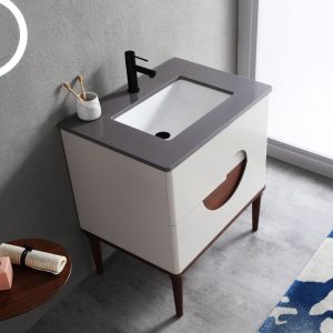 The Burano 30 inch Beige Freestanding Bathroom Vanity has a gray countertop, white sink, and black faucet. A marble cup with toothbrushes rests on the counter, while part of a blue patterned rug appears on the floor.