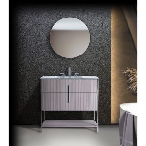 A modern bathroom features a textured dark wall, round mirror above the Serenity 24 Bathroom Vanity with vertical lines and a white sink, plus a glimpse of a bathtub and towel on the right.