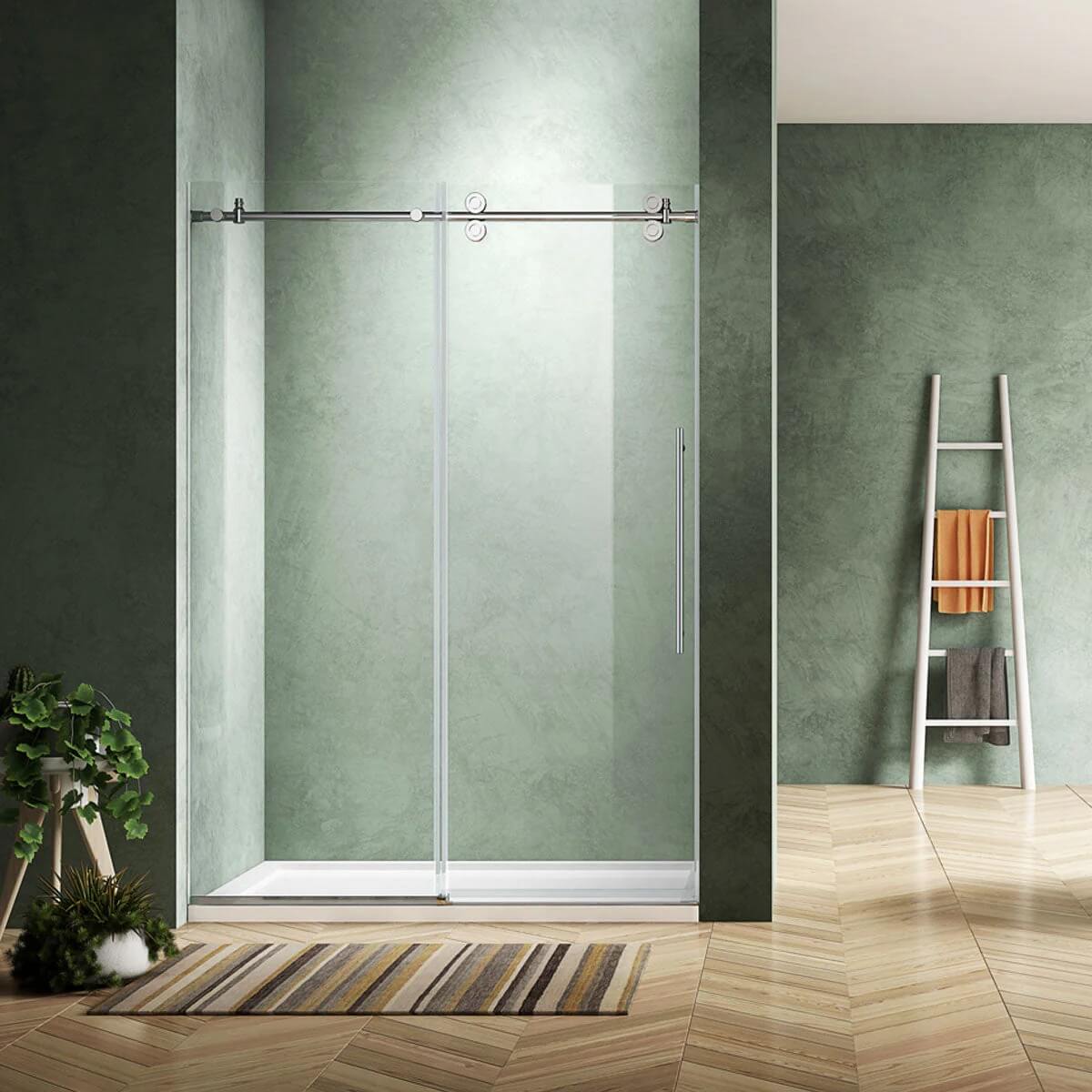 Modern bathroom features the Bhavana 48" Frameless Sliding Shower Door, green textured walls, a striped rug, potted plant, and white ladder shelf with towels. Light wood herringbone flooring adds warmth to the space.