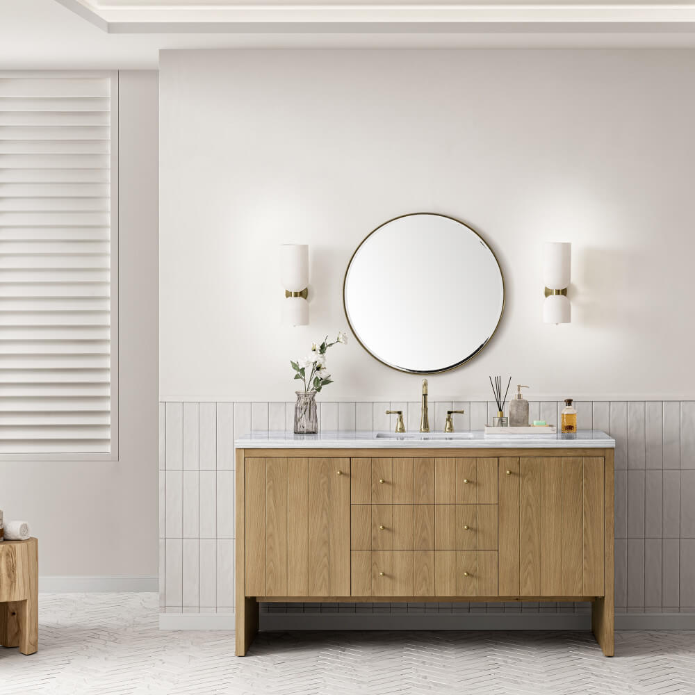 Modern bathroom featuring the Hudson 60 inch Single Vanity Cabinet in Light Natural Oak with a marble countertop, round mirror, wall sconces, and decorative accents. Light tiles and neutral walls complete the clean, minimalist design.