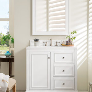 Sunlight spills through blinds onto a bright bathroom, highlighting a De Soto 36 inch Bathroom Vanity Cabinet in white equipped with a sink, three drawers, and a cabinet. Potted plants and toiletries rest on the counter beneath the mirror. A chair and towel rack are also partially visible.