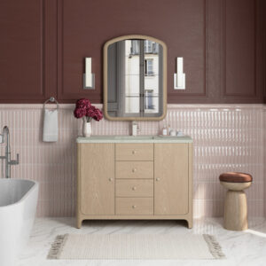 A modern bathroom showcases the Gracyn 48 inch Single Bathroom Vanity, a curved mirror, wall sconces, pink lower wall tiles with dark red above, a flower vase, towel ring, stool, and a white bathtub for a stylish finish.