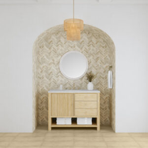 The Marigot 48 inch Single Vanity Cabinet includes a round mirror, wooden cabinet, and beige herringbone tile accent wall. A pendant light is overhead and folded towels sit on the shelf below. Neutral tones enhance its warm, minimalist design.