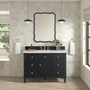 An elegant bathroom showcases the Lorelai 48 Single Vanity Cabinet with brass knobs, a white countertop, and a decorative mirror. Pendant lights hang overhead, complemented by light-colored tile walls and wood flooring. White towels on gold rings complete the look.