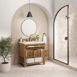 A modern bathroom features the Malibu 36 inch Bathroom Vanity Cabinet in Amber Birch with open drawers displaying folded towels. A round mirror and black pendant light add style, while a glass shower enclosure is on the right and a potted plant sits to the left against geometric-patterned walls.