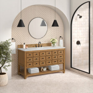 The bathroom includes a Malibu 60 inch Single Bathroom Vanity Cabinet in Amber Birch with ample drawers, complemented by a round mirror, two pendant lights, and a potted plant. A geometric-patterned wall and a glass shower with tiled walls on the right complete the space.