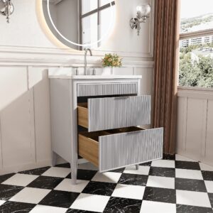 The Aveline 30 Inch Freestanding Bathroom Vanity With Top features two open drawers, a round mirror above, a vase of flowers on the counter, wall sconces, a black-and-white checkered floor, and a window with brown curtains on the right.