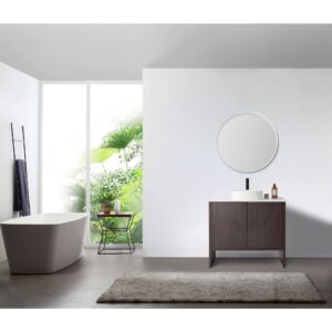 Modern bathroom featuring the Celle 36 Inch Bathroom Vanity With Vessel Sink, a freestanding white bathtub, round mirror, small plant table by a large window, gray rug on the floor, and abundant natural light.