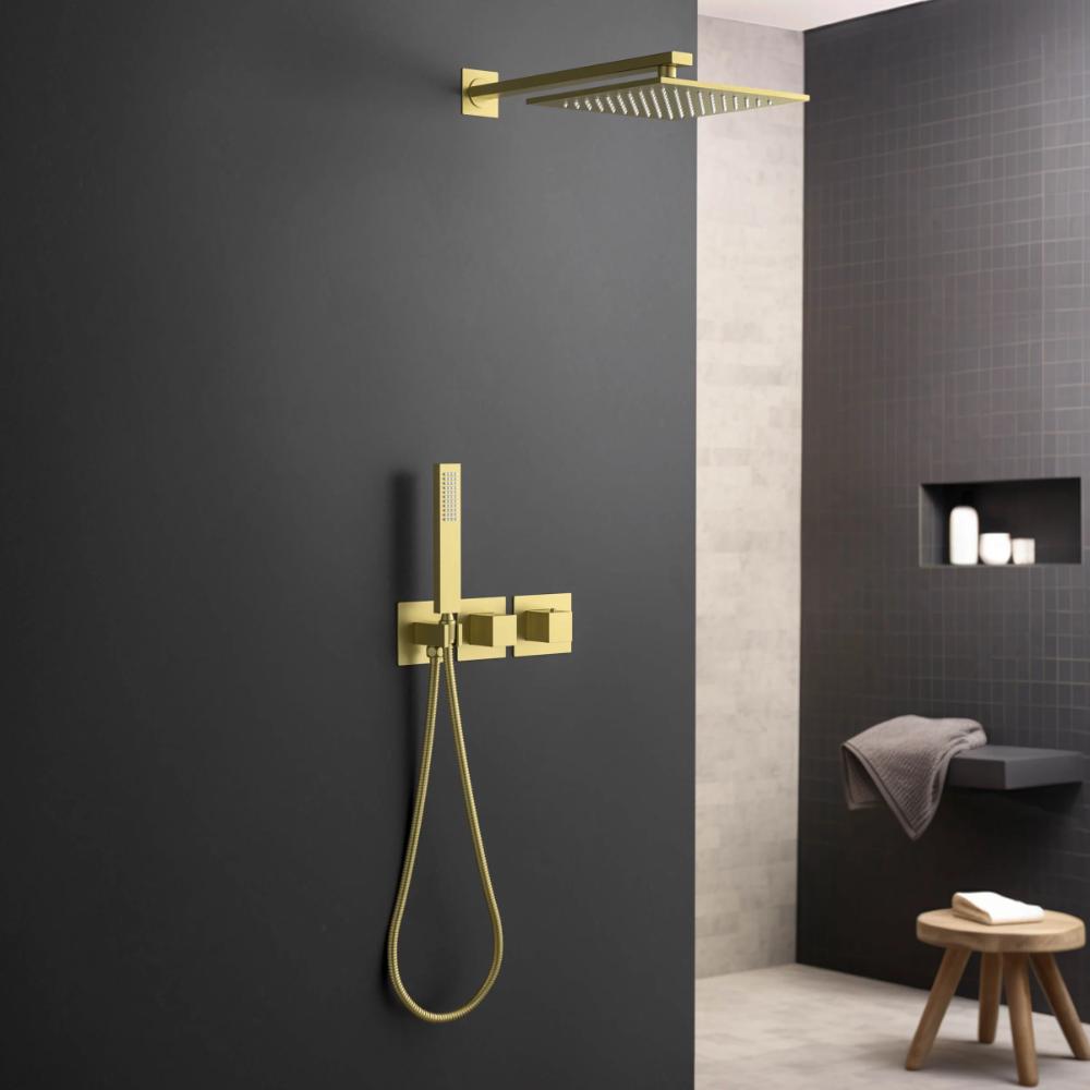 Modern bathroom with a matte black wall featuring a gold rain shower head, handheld shower, and faucet set. In the background, shelves hold toiletries and a towel rests on a wooden stool.
